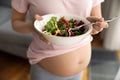 Expectant mother holding bowl with fresh vegetable salad