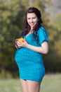 Expectant mother holds tangerines looks at camera smiling
