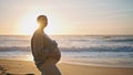 Expectant mother posing sunset standing beach caressing belly. Pregnant woman Royalty Free Stock Photo