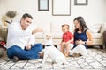 Expectant Mother And Son Looking At Man Feeding Puppy At Home