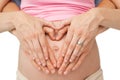 Expectant parents making a heart shape on mothers baby bump