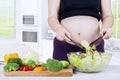 Expectant woman prepares salad with a bowl