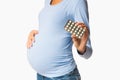 Expectant woman showing pills blister pack, white background Royalty Free Stock Photo