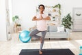 Expectant young lady doing her morning yoga practice, standing in tree pose, feeling peaceful at home Royalty Free Stock Photo