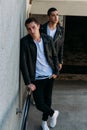 mans posing near railing. Handsome young mans in stylish black clothes and white shoes posing near a railing. friendship Royalty Free Stock Photo