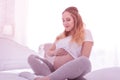 Young long-haired pregnant woman in a white t-shirt looking amused Royalty Free Stock Photo
