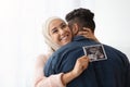 Expecting Baby. Cheerful Pregnant Muslim Woman Hijab Holding Ultrasound Picture, Hugging Husband Royalty Free Stock Photo