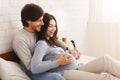 Expecting couple holding headphones on pregnant belly playing music to baby Royalty Free Stock Photo