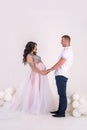 In expecting. Happy pregnant pair in fashion clothes posing in studio