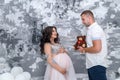 In expecting. Happy pregnant pair in fashion clothes posing in studio