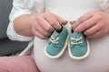 Expecting mother holding tiny baby shoes on her belly. Maternity prenatal care and pregnancy concept Royalty Free Stock Photo