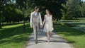 Expecting young couple gazing into each others eyes walking through green park. Royalty Free Stock Photo