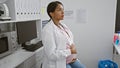 Expecting young scientist, hispanic woman seriously engaged in research, touching pregnant belly at lab