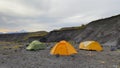 Expeditionary extreme tents of different colors stand in a small ravine on the lava fields of Kamchatka