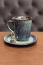 Expensive beautiful blue ceramic coffee mug on wooden table in coffee shop. A glass of black tea on a wooden surface against a