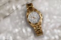 expensive beautiful ladies gold watch with a metal strap and a chronometer on a marble background with bokeh in