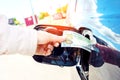 Expensive fuel concept. Rise in fuel price. Hand inserting a hundred dollar bill into the gas tank flap