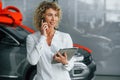 Expensive gift. Woman with curly blonde hair is in autosalon Royalty Free Stock Photo