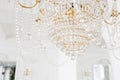 Expensive interior. Large electric chandelier made of transparent glass beads. White ceiling decorated with stucco Royalty Free Stock Photo