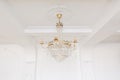 Expensive interior. Large electric chandelier made of transparent glass beads. White ceiling decorated with stucco Royalty Free Stock Photo