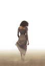 pretty black woman walking away in the mist and dust. sadness and grief concept art. Royalty Free Stock Photo
