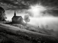 A small church in the countryside on a foggy morning with beautiful sunlight in front, black and white photo - generative ai