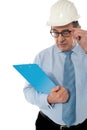 Experienced achitect in hardhat studying files. Royalty Free Stock Photo