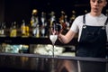 An experienced bartender in an apron fills a glass of champagne at the bar