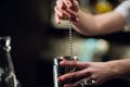 An experienced bartender prepares an alcoholic cocktail. No face, close-up, copy space.