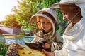 An experienced beekeeper transfers knowledge of beekeeping to a small beekeeper. The concept of transfer of experience. Royalty Free Stock Photo