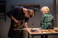 An experienced carpenter shows the work of various tools to his son in the workshop. Royalty Free Stock Photo