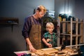 an experienced carpenter shows the work of various tools to his son in the workshop. Royalty Free Stock Photo