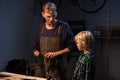 an experienced carpenter shows the work of various tools to his son in the workshop. Royalty Free Stock Photo