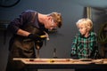 An experienced carpenter shows the work of various tools to his son in the workshop. Royalty Free Stock Photo