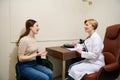 Experienced mature female doctor writes down the patient`s complaints, fills out a medical card during an appointment in office i Royalty Free Stock Photo