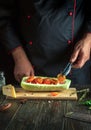 Experienced chef adds a tomato to the zucchini. The concept of cooking a national stuffed squash boat or marrow in a restaurant Royalty Free Stock Photo