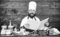 Experienced chef cooking excellent dish. This recipe is just perfect. Man bearded hipster read book recipe near table Royalty Free Stock Photo