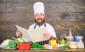 Experienced chef cooking excellent dish. This recipe is just perfect. Man bearded hipster read book recipe near table Royalty Free Stock Photo