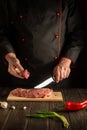 Experienced chef cuts beef raw meat on a cutting board before barbecue. Preparing a delicious meal in the kitchen Royalty Free Stock Photo