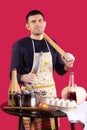 Experienced chef displaying kitchen utensils. Male chef is holding a knife on a red background. Hospitality staff