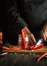 Experienced cook preparing fresh vegetables and peppers in the kitchen. Slicing with a pepper knife on a wooden cutting board. Royalty Free Stock Photo