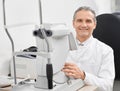Experienced doctor ophthalmologist posing with slit lamp.
