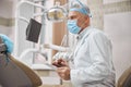 Professional dental expert holding a tablet in his office