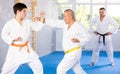 Elderly karate fighter engaging kumite with young rival in training room