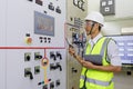 Experienced electrician working in power plant control room. Engineer working on the checking status switchgear electrical energy Royalty Free Stock Photo