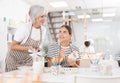 Experienced female ceramicist teaching young girl to paint ceramics in pottery studio Royalty Free Stock Photo