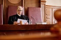 Experienced female judge in black gown reading juridical paper documents Royalty Free Stock Photo