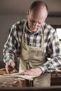 Experienced instrument maker carefully using his hand to check a piece of a mandolin