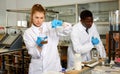 Experienced male and female scientists with glass test tubes
