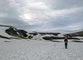 Experienced male hiker hiking alone into the wild admiring geothermal landscape covered with snow, heavy backpack. Travel Royalty Free Stock Photo